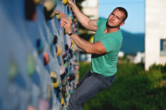 young man climbing wall rock outdoors