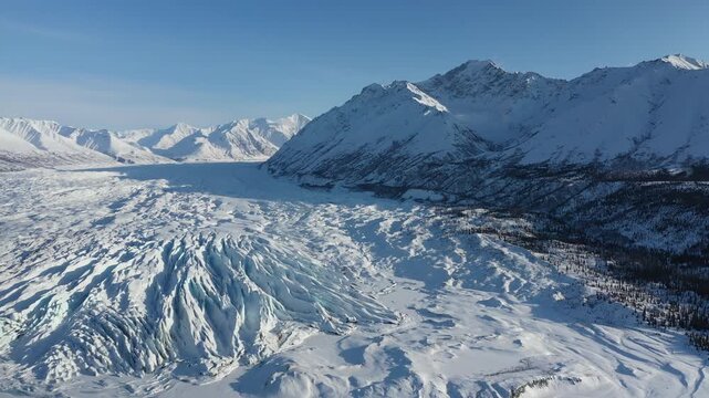 High Aerial View of Snow-Covered Glacier and Forest Valley Below Mountain Range