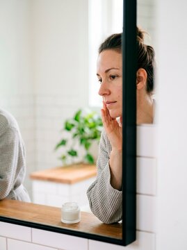 Woman Reflecting in Bathroom Mirror with Natural Light
