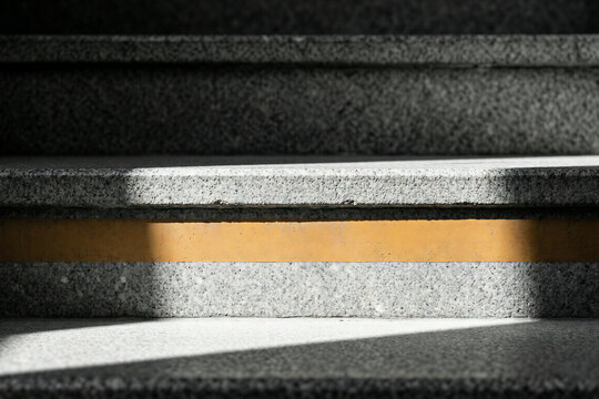 Sunlight beam on granite stone stairs with yellow safety strip