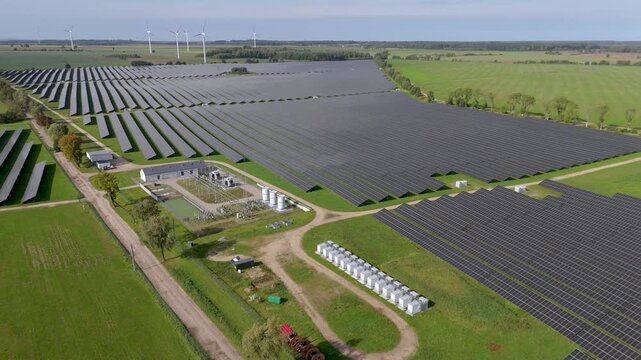 Aerial drone shot of a large-scale solar park with battery energy storage system and wind turbines highlighting green energy infrastructure