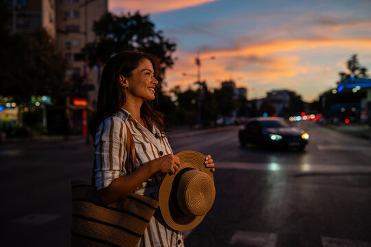 Woman smiling on city street at sunset