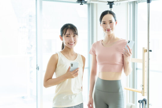 スマートフォンを持つ女性　ピラティス、ヨガ、スタジオ