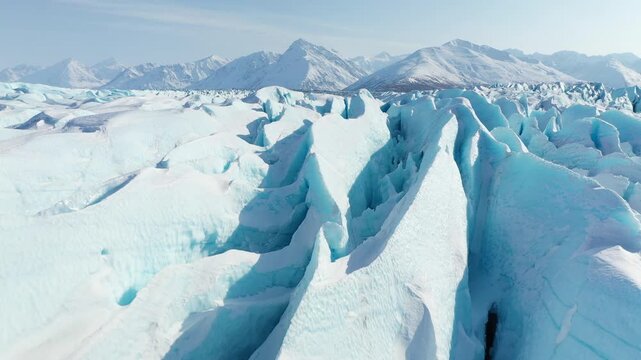 Low Drone Pass Over Deep Blue Glacial Crevasses and Snow-Capped Mountains