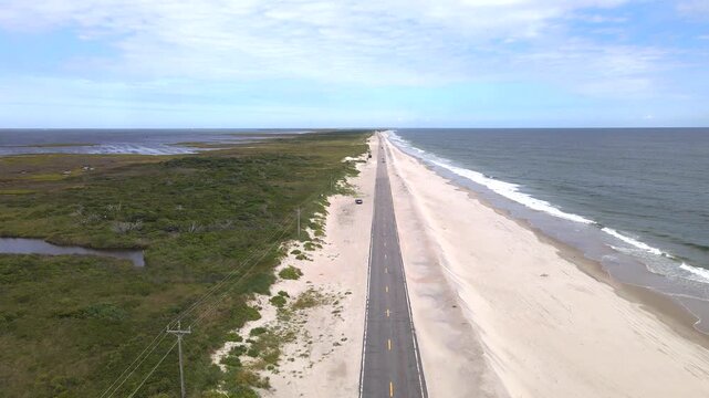 coastal road separates sandy dunes from wetlands during an Outer Banks aerial flight.
