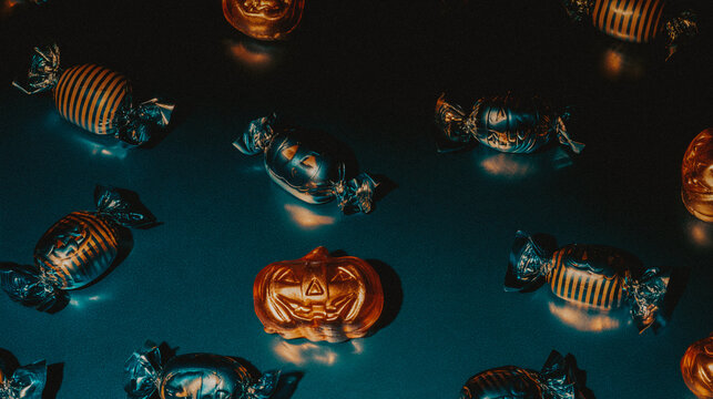 Dark Halloween candy pattern featuring glossy pumpkin shaped candy and striped wrapped sweets on a deep blue black background, creating sophisticated moody seasonal aesthetic for packaging and design.