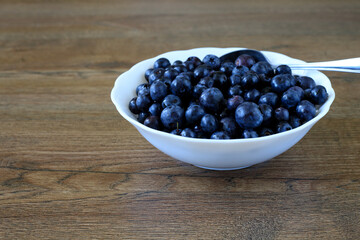 Fresh Bilberries in White Bowl with Spoon on Wooden Table © yaviki