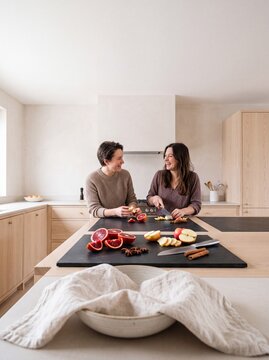 Happy Young Lesbian Couple Cooking and Laughing Together in Modern Bright Kitchen