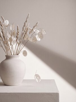 Minimalist still life of dried lunaria and wheat stalks in a ceramic vase with soft diagonal sunlight shadows