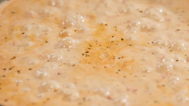Tomato and garlic sauce with cream and spices bubbling and simmering in pan in home kitchen; process of making tomato pasta; preparation of delicious and healthy Italian meal; food closeup