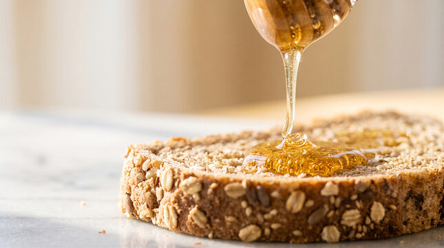 Pouring fresh golden honey from wooden dipper onto whole grain seeded bread slice for healthy breakfast