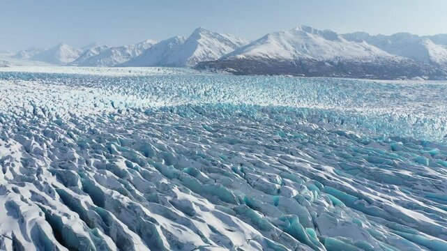 Slow Aerial Glide Over Blue Glacier Crevasses and Snowy Mountain Range