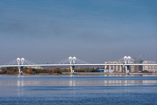 Cable‑stayed bridge over Zeya river, capturing calm water, clear light and distant urban skyline