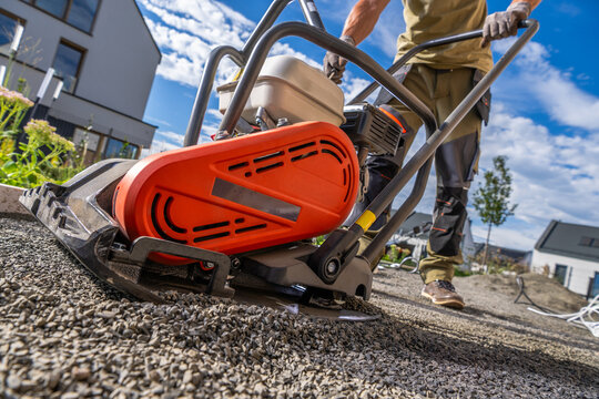 Worker compacting a gravel base with a vibrating plate compactor