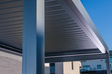 Modern metal pergola with a louvered roof against a blue sky © Tomasz Zajda