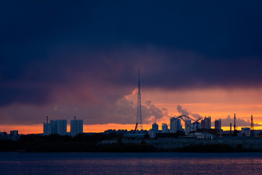 Dramatic sunset over Blagoveshchensk city skyline across Zeya river, capturing vivid sky colors and calm reflective water