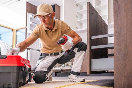 Kitchen installer reaching for tools beside an open cabinet
