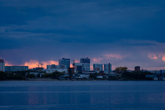 Dramatic sunset over Blagoveshchensk city skyline across Zeya river, capturing vivid sky colors and calm reflective water