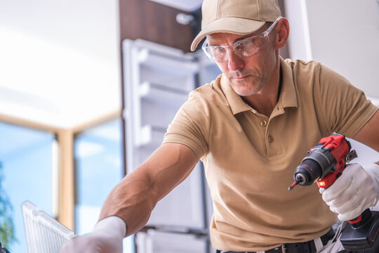 Kitchen installer holding a cordless drill beside a cabinet
