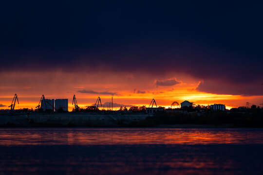 Dramatic sunset over Blagoveshchensk city skyline across Zeya river, capturing vivid sky colors and calm reflective water