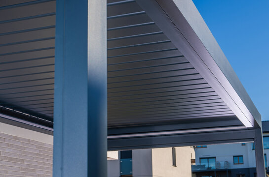 Modern metal pergola with a louvered roof against a blue sky