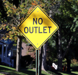 Yellow diamond No Outlet road sign on metal pole against trees © Lacy