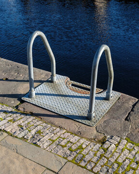 Metal access ladder positioned on the stone edge of the historic Caledonian Canal located in the town of Fort Augustus within the Scottish Highlands