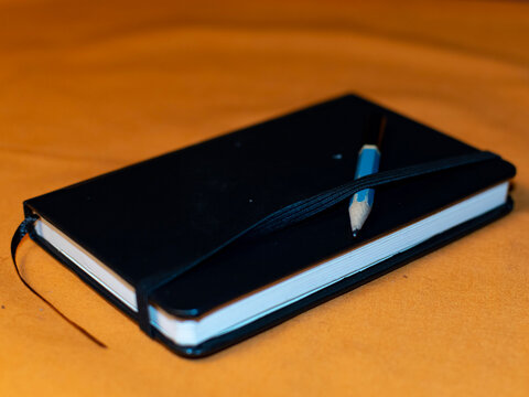 Small drawing pad on an orange surface with copy space in the top left corner. 