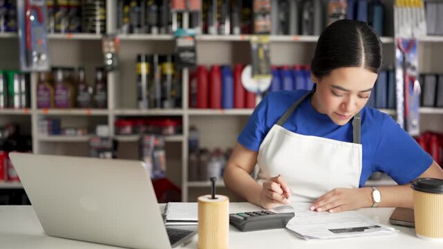 Young latina business owner working on inventory and finances in her auto parts store