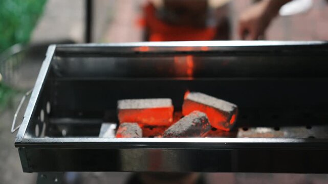 Glowing charcoal briquettes in metal grill