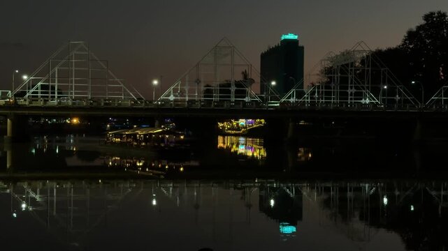 Bridge and city skyline reflecting on river in Chiang Mai