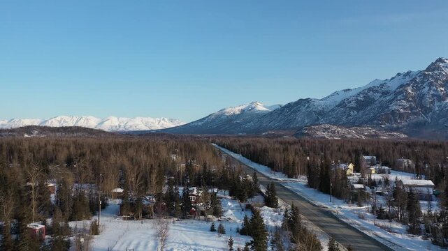 Wide Establishing Shot of Winter Forest Town with Snow-Capped Mountains