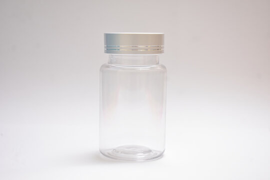 Empty clear plastic medicine jar bottle with silver cap isolated on plain white background