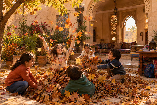 Children Playing In Autumn Leaves After Finishing Homework