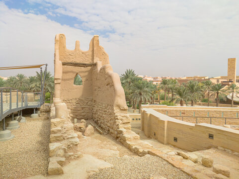 Modern structures protect the ruins of Diriyah of Riyadh in Saudi Arabia. the first Saudi capital, showcasing Saudi Arabia's rich history and cultural heritage amidst palm trees and a modern cityscape