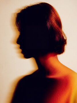 Artistic silhouette portrait of a woman with red hair and warm lighting creating a shadowed profile effect