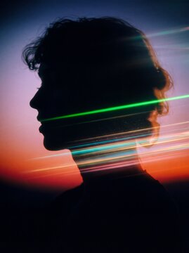Silhouette of a person against a colorful sunset background with dynamic light streaks crossing the frame