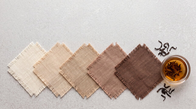 Tea Dyeing Concept with Neutral Fabric Swatches and Tea Leaves