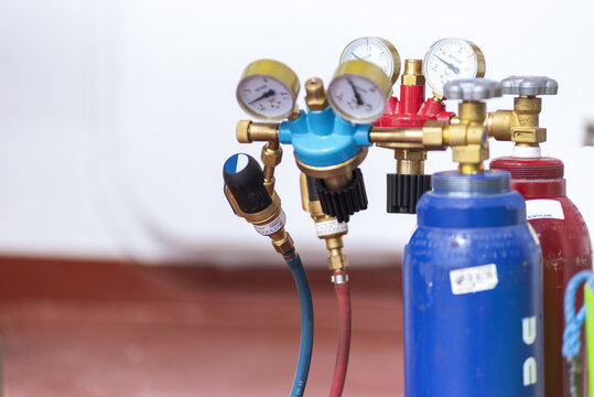 Detailed view of industrial acetylene and oxygen gas cylinders fitted with pressure gauges, pressure regulators and safety valves for gas welding operations.