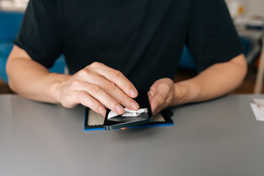 Person disinfecting electronic device for personal hygiene. Concept of digital cleanliness, gadget maintenance, preventing spread of bacteria. Close-up with selective concept of hands and phone
