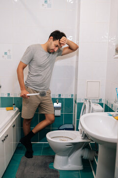 Vertical portrait of tired man overwhelmed by domestic work and unpleasant duties. Concept of household chores, hygiene, feeling disgusted by dirty cleaning tasks. Full length view