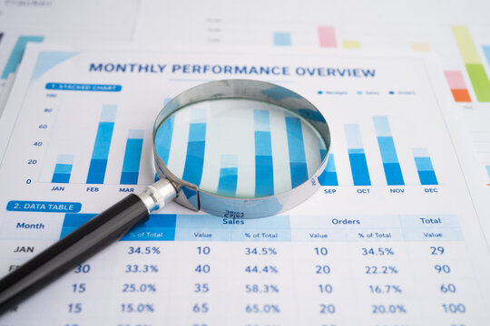 Magnifying glass on spreadsheet and graph paper.