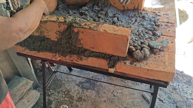 Female Hands Smearing Mud Mortar Evenly Across Clay Bricks