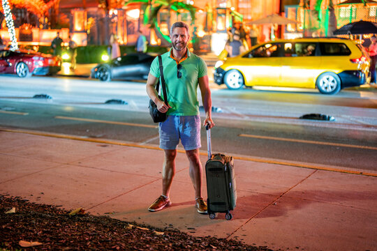 Traveler enjoy summer trip. Hispanic tourist traveler walking on city street. Tourist with suitcase in tropical city. Man 40s traveler. Tourist on summer vacation. Traveler luggage for summer trip