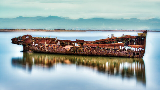The rusty ancient ship wreck lying in the mud in the harbour in Motueka Nelson