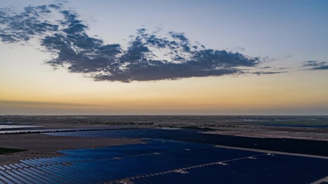 Solar photovoltaic panels at sunrise/sunset; wind turbine power plant; new energy