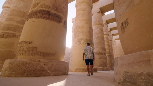 Man Looking At The Colossal Sandstone Columns Inside Great Hypostyle Hall At The Karnak Temple Complex In Luxor, Egypt. Low-angle, Rotating Shot