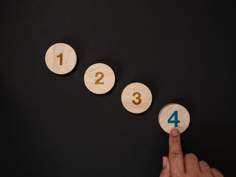 Hand selects the fourth stage in numbered four-step sequence on dark background, representing completion, business progress, workflow milestones, decision making and project success concept.