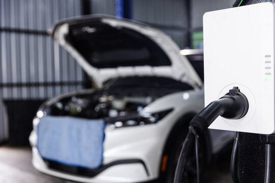 EV Wallbox Charger with an Open-Hood Car in an Automotive Workshop