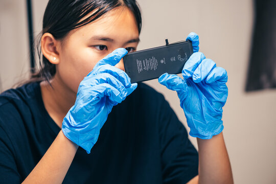 Female technician replaces smartphone lithium battery for hardware repair concept. Conceptual backdrop for phone repair service, right to repair microelectronics, and green circular economy 